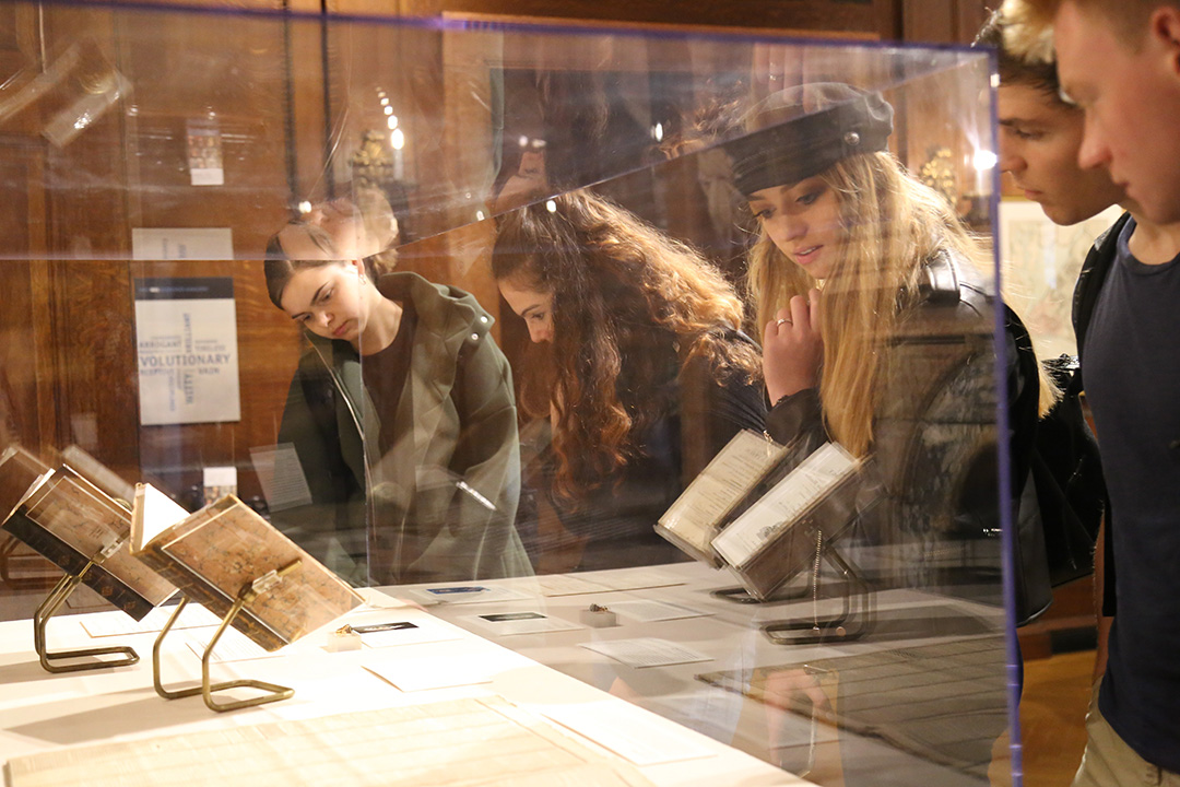 Students looking at some of George Washington's old books through a glass case