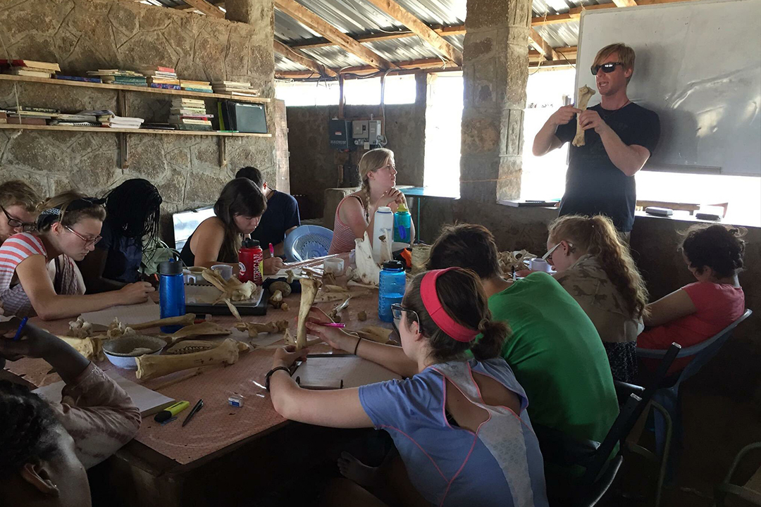 Students and staff talking at a table on site at the Koobi Fora site, Kenya